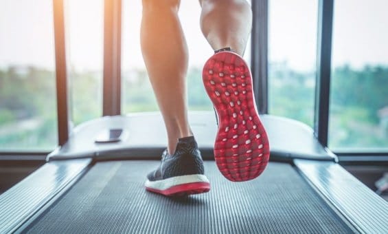 person running on treadmill in sneakers with red bottoms