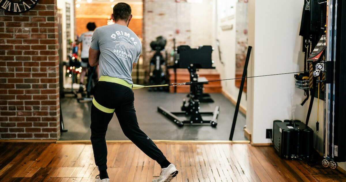 a golfer with a harness doing a swing mechanics with physical therapy