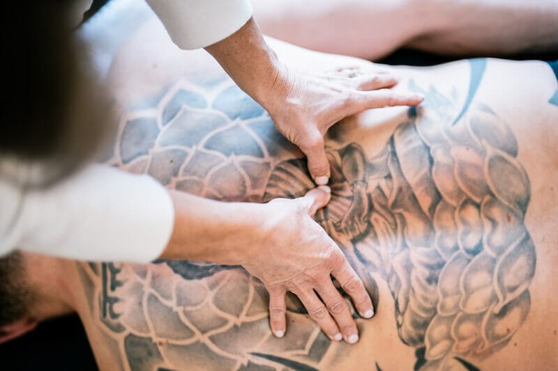 patient with back tattoos being worked on by physiotherapist