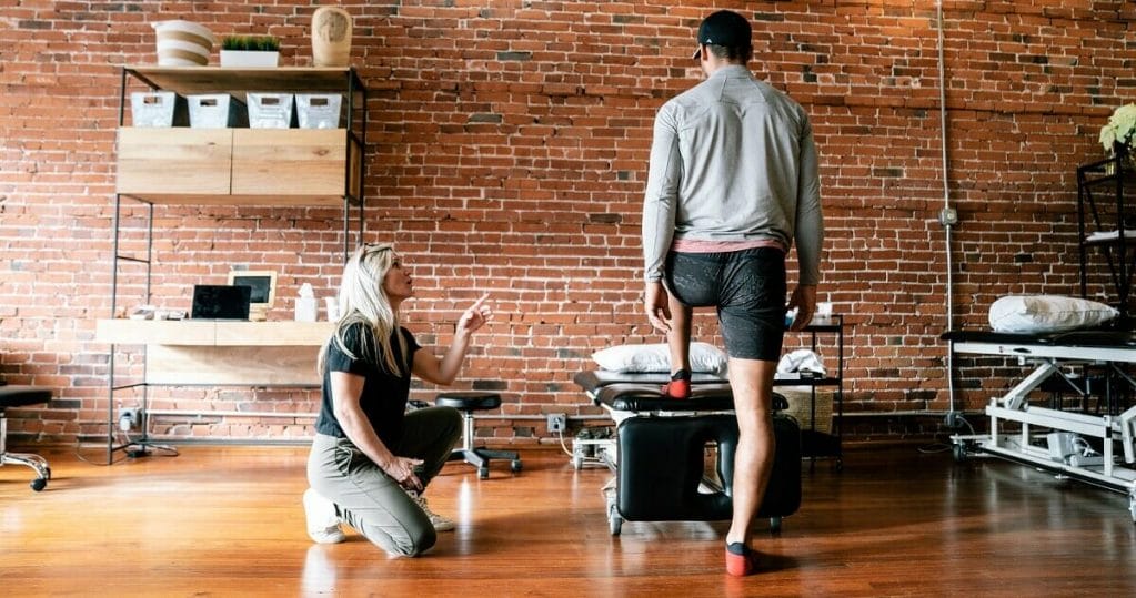 a woman therapist teaching a right physical therapy posture exercises to a man with cap