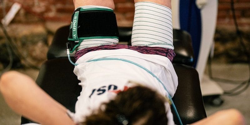 female blood flow restriction therapy patient on table with blue elastic band around thighs